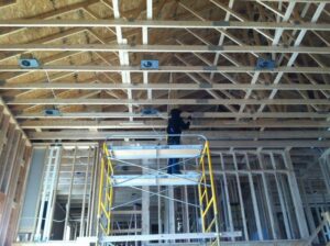 An electrician on scaffolding installing ceiling wiring during construction by Cannizzo Electric, Inc. in Rochester, NY.