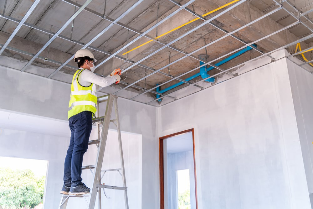 An electrician installing new electrical wiring in a ceiling at a construction site by Eon Electric in Orem, UT.