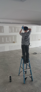 An electrician from Essential Electric LLC on a ladder installing ceiling wiring during a job in Lancaster, KY.