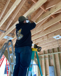 An electrician on a ladder installing ceiling wiring and fixtures for Island Power Company LLC in South Kingstown, RI.