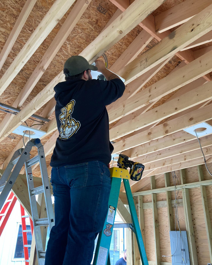 An electrician on a ladder installing ceiling wiring and fixtures for Island Power Company LLC in South Kingstown, RI.