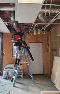 An electrician on a ladder installing new wiring in a ceiling for LANG ELECTRIC in Knoxville, TN.