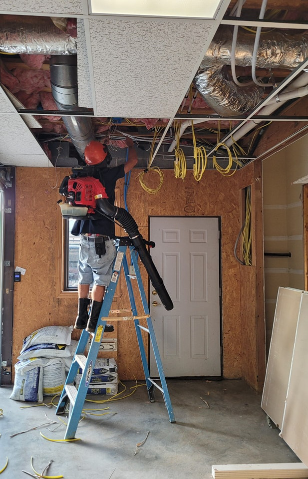 An electrician on a ladder installing new wiring in a ceiling for LANG ELECTRIC in Knoxville, TN.