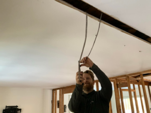 An electrician installing new wiring in a ceiling during a renovation project by MDMartin Electrical LLC in Philadelphia, PA.