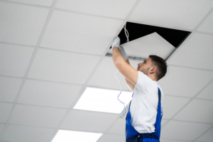 An electrician installing or repairing wiring in a ceiling grid for Polk Electric, LLC in Rock Hill, SC