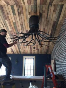 An electrician installing a large, decorative chandelier for President, Cannizzo Electric, Inc. in Rochester, NY.