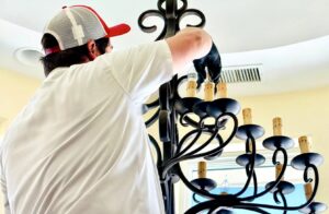 An electrician from Mister Sparky of Columbia installing a large chandelier in a home in West Columbia, SC.