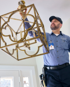 An electrician installing a decorative chandelier for a client of Mr. Electric of Tulsa - Metro in Tulsa, OK.