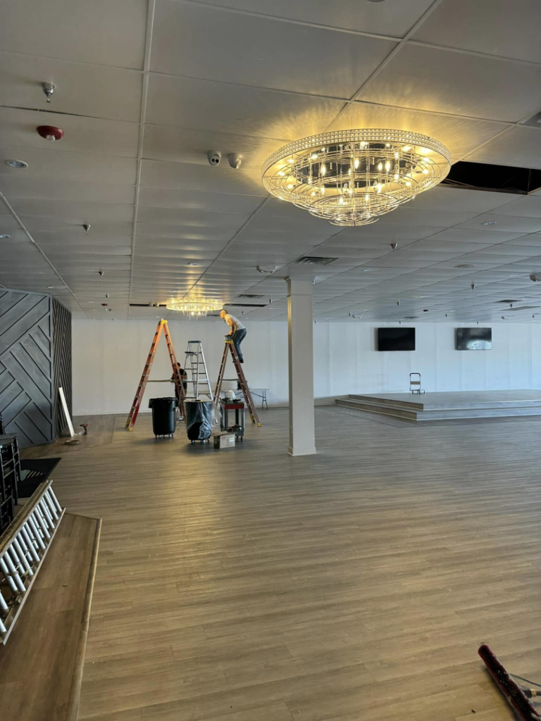 An electrician from Power Electric installing a large chandelier in De Leon springs, FL.