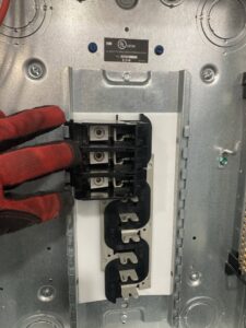 A gloved hand of an electrician from Diaz Techician LLC in Chicago, IL, installing a circuit breaker in an electrical panel.
