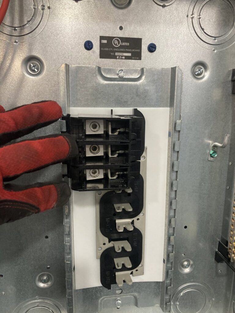 A gloved hand of an electrician from Diaz Techician LLC in Chicago, IL, installing a circuit breaker in an electrical panel.