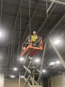 An Ultralight Electrician on a scissor lift installing commercial lighting and wiring in a large building in Houston, TX.