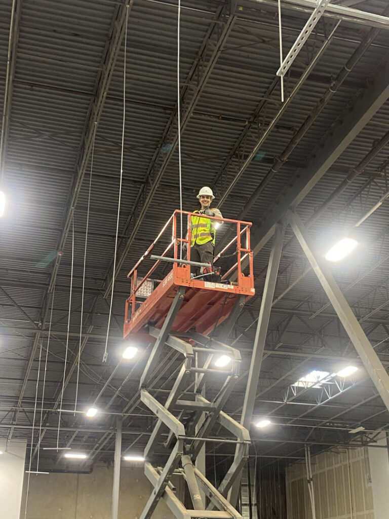 An Ultralight Electrician on a scissor lift installing commercial lighting and wiring in a large building in Houston, TX.