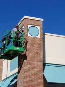 An electrician in a lift installing or repairing commercial signage on a building by Discount Electrical Service of Franklin in Franklin, TN