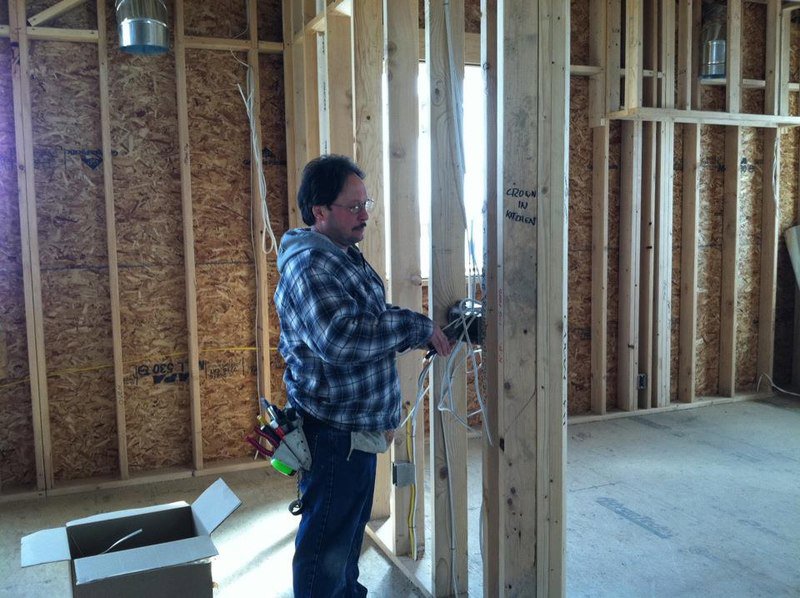 An electrician installing a complex, multi-piece chandelier for President, Cannizzo Electric, Inc. in Rochester, NY.
