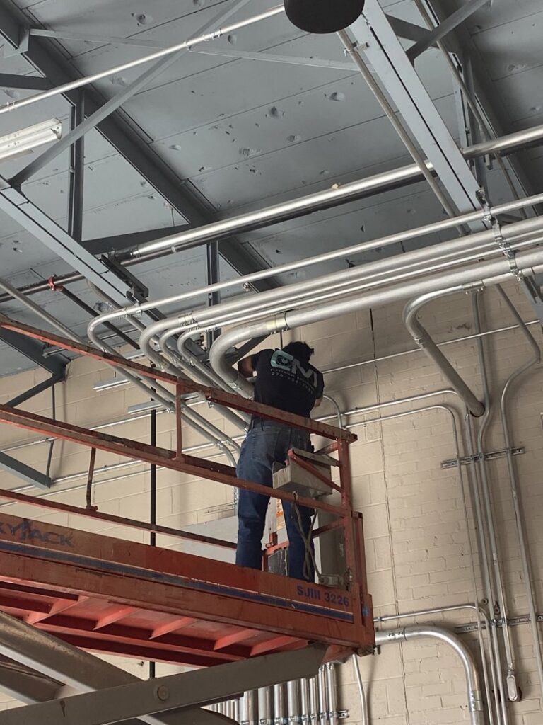 An electrician installing electrical conduit on a commercial ceiling for CM Electrical Solutions in Elizabethtown, KY.
