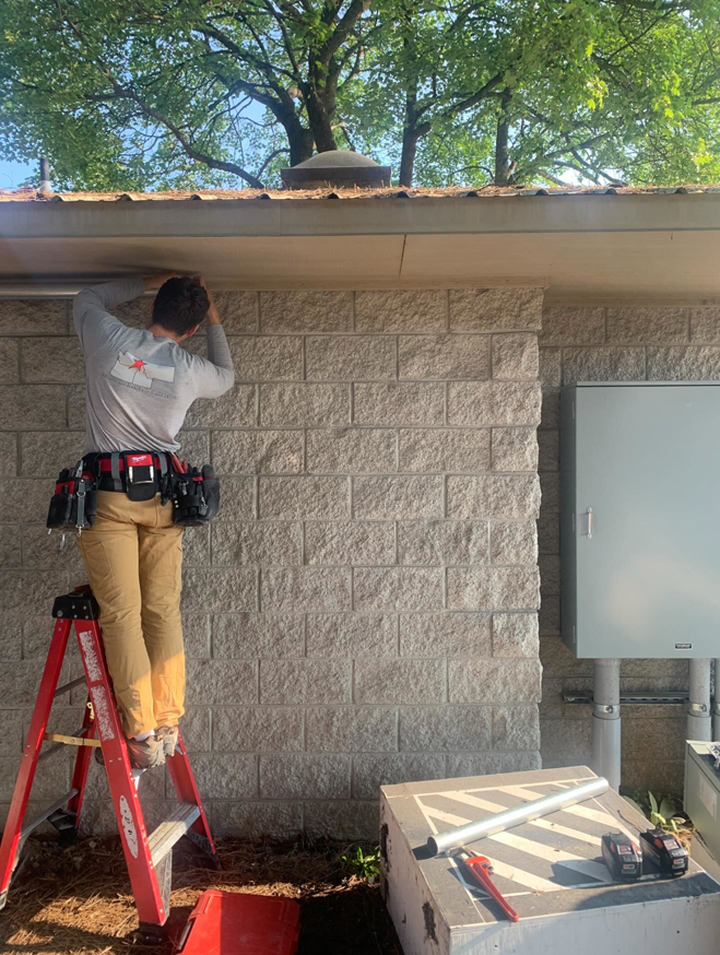 An electrician on a ladder installing conduit on an exterior wall for Interstate Electrical Contractors in Dalton Gardens, ID.