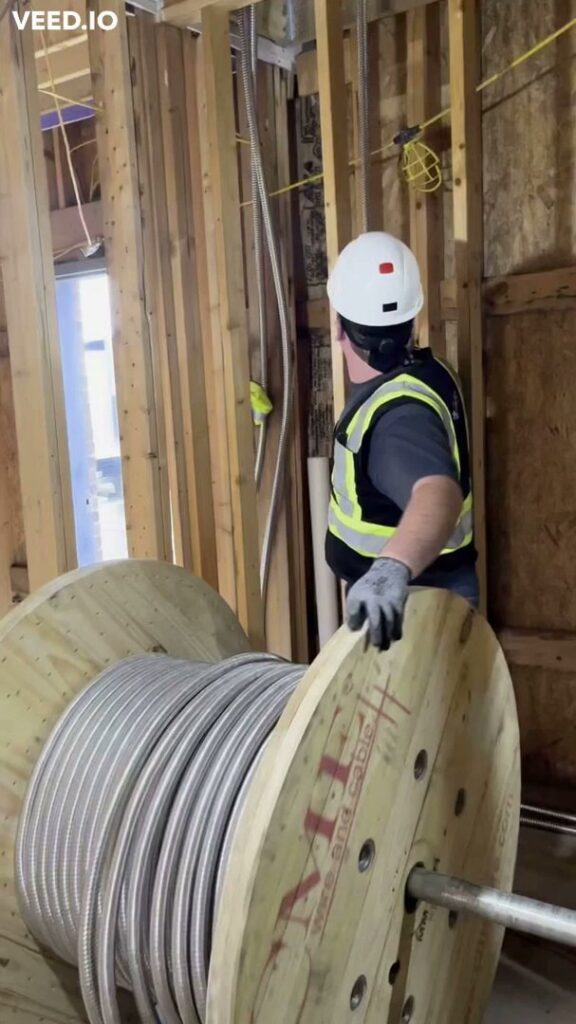 An electrician installing flexible conduit from a large spool in a new construction project by Pro 1 Electric, Inc. in Parkersburg, WV