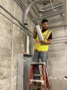 An electrician installing electrical conduits and a panel on a concrete wall for Electrical Power Source in Fresno, CA.