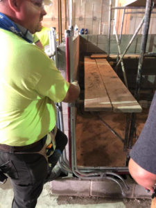 An electrician from Azure Electrical installing electrical conduits into a wall at a job site in Indianapolis, IN