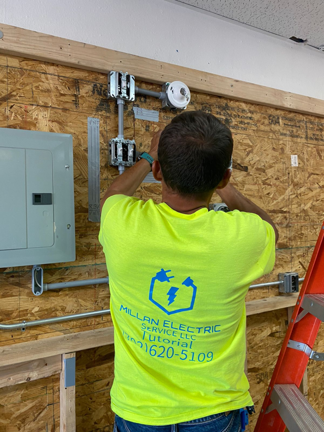 An electrician installing electrical conduit and boxes on a wooden wall at Millan Electric Service llc in Las Vegas, NV