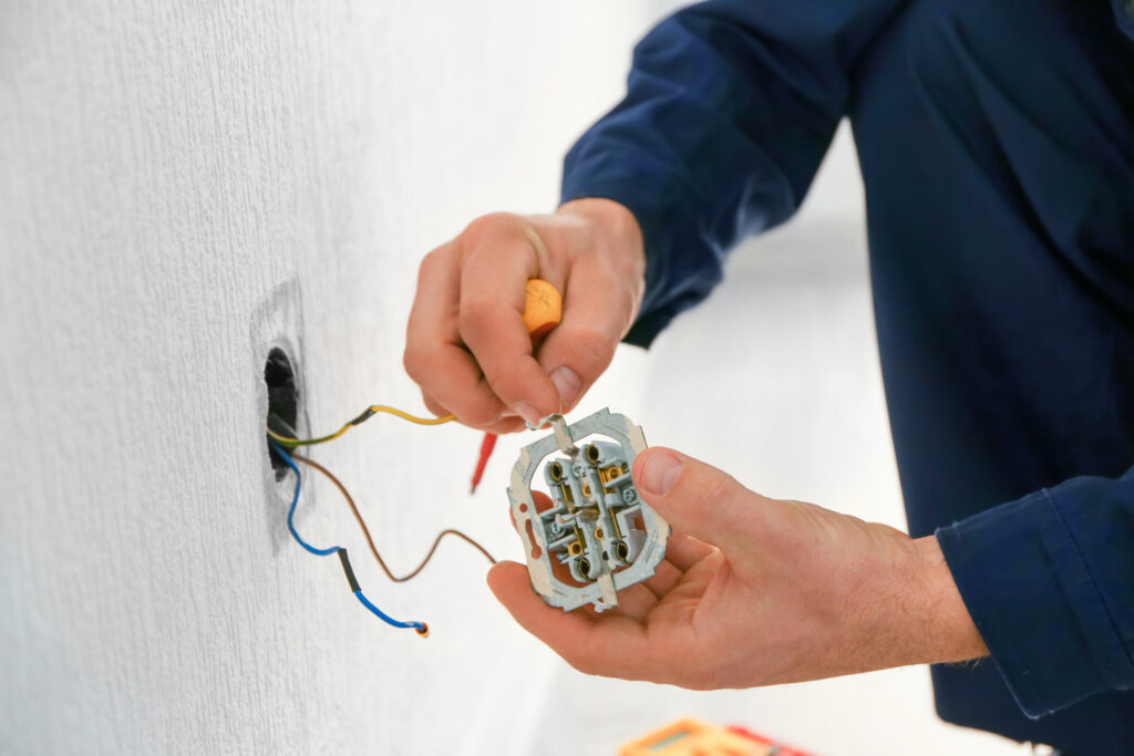 An electrician installing or repairing an electrical outlet, a service offered by Next Level Contracting LLC in Dayton, OH