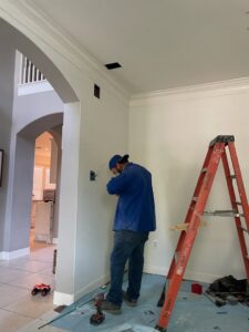 An electrician from Powered By H installing an electrical outlet or switch box in a home in Houston, TX.