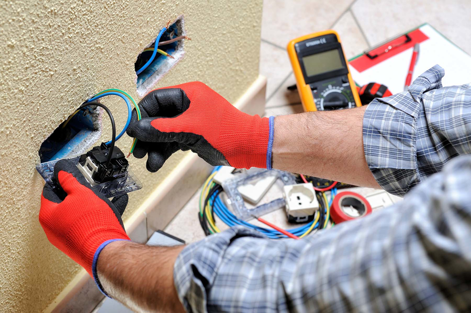 An electrician installing an electrical outlet with tools nearby for WireMasters Electric, Inc. in Miami, FL.
