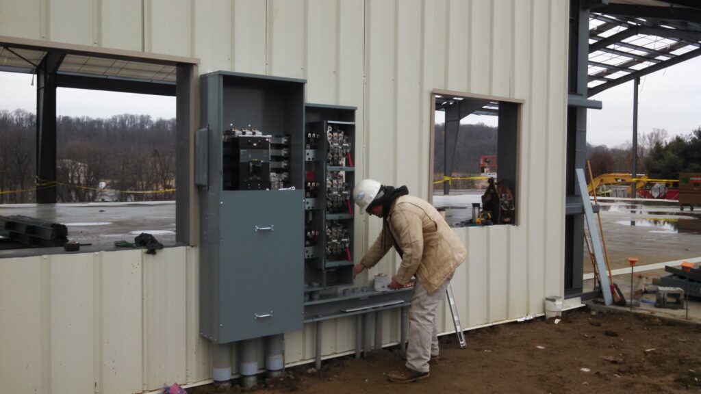 An electrician from D&T Electric LLC installing an electrical panel on a commercial building in Lancaster, PA.