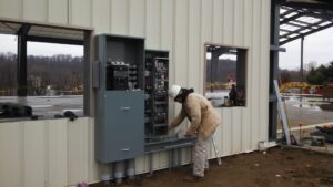 An electrician from D&T Electric LLC installing an electrical panel on a commercial building in Lancaster, PA.