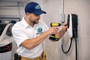 An electrician from Detroit Speedy Electrician installing an EV charging station in a garage in Detroit, MI.