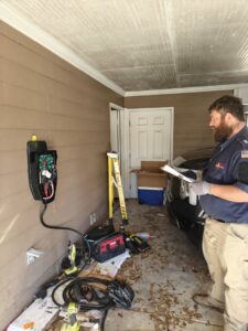 An electrician installing an electric vehicle (EV) charging station in a residential garage for Sherrill Company, LLC Electrical Contractors in Columbus, GA.