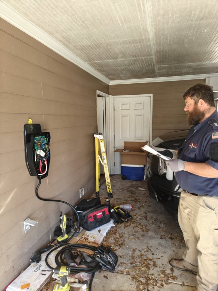 An electrician installing an electric vehicle (EV) charging station in a residential garage for Sherrill Company, LLC Electrical Contractors in Columbus, GA.