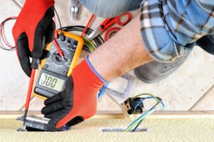 An electrician installing a floor electrical outlet with tools nearby for Polsley Electric Company in Omaha, NE