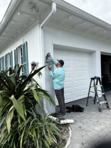 An electrician from Bee Electrical Contracting installing an outdoor light fixture on a garage in Port Saint Lucie, FL.