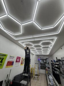 An electrician from Positive Electricians installing hexagonal LED lights on a ceiling in Van Nuys, CA.