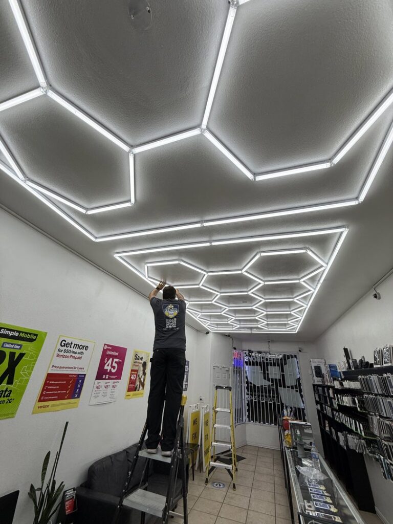 An electrician from Positive Electricians installing hexagonal LED lights on a ceiling in Van Nuys, CA.
