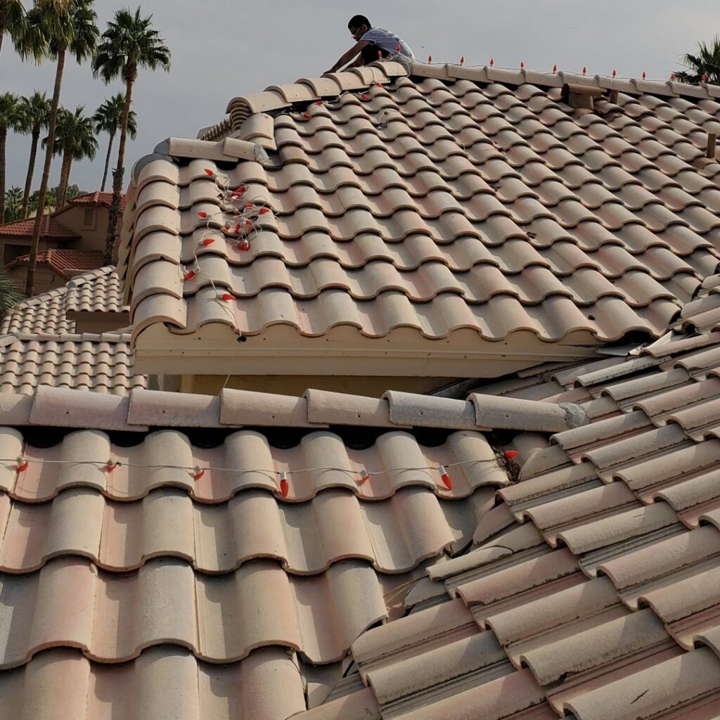 An electrician from GET LIT Electrical Services LLC installing holiday lights on a residential roof in Glendale, AZ.