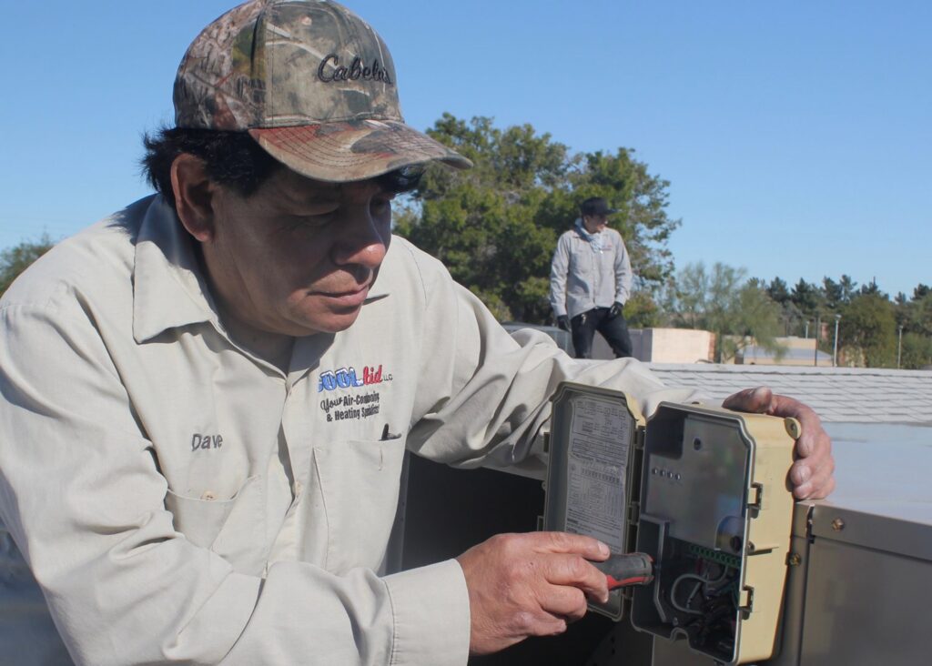 An electrician installing or repairing HVAC wiring at the disconnect box for Cool Aid Air Conditioning in Scottsdale, AZ.