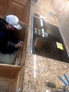 An electrician installing a kitchen cooktop and making electrical connections at a home by True Vine Electric in Raleigh, NC