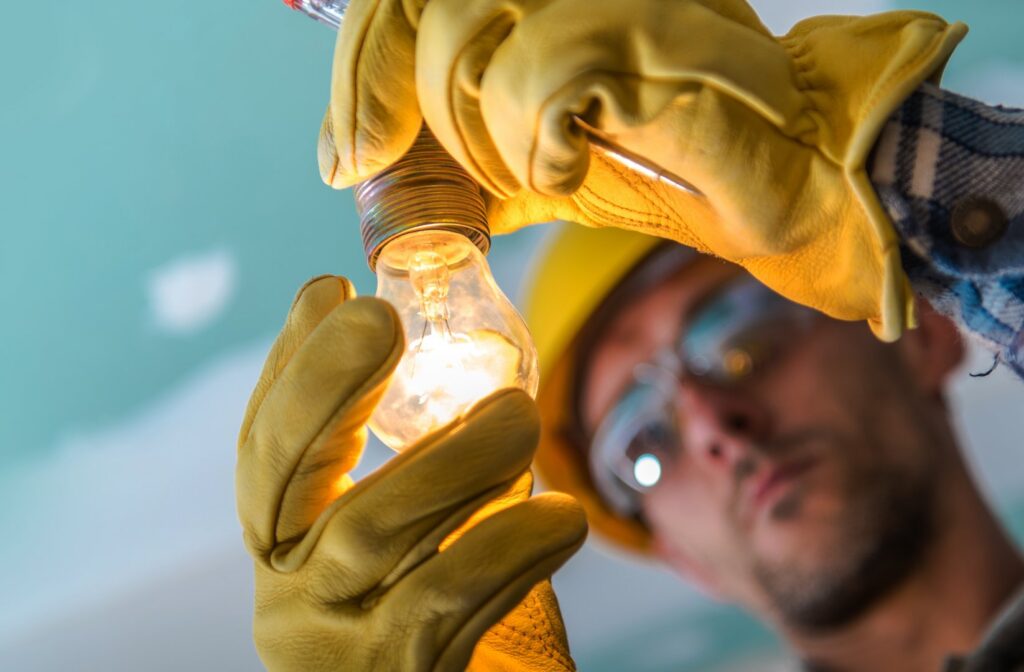 An electrician installing a light bulb in a ceiling fixture, a service provided by Next Level Contracting LLC in Dayton, OH