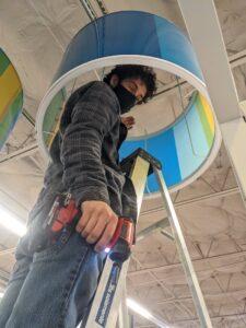 An electrician on a ladder installing an overhead light fixture for Cardinal Electric in Sayreville, NJ