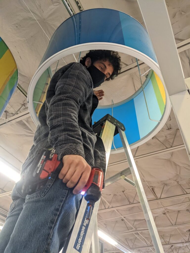 An electrician on a ladder installing an overhead light fixture for Cardinal Electric in Sayreville, NJ