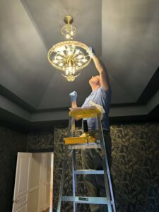 An electrician installing a new light fixture in a home for Gloudeman Electric in Mount Pleasant, SC
