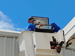 An electrician from Jesse's Electric installing or repairing a light fixture from a bucket truck in Laredo, TX.