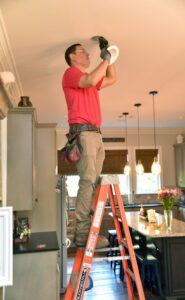 An electrician installing a recessed light fixture in a kitchen ceiling for MetroPower, Inc. in Albany, GA.
