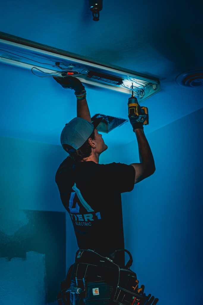 An electrician from Tier 1 Electric installing an overhead light fixture in Boise, ID