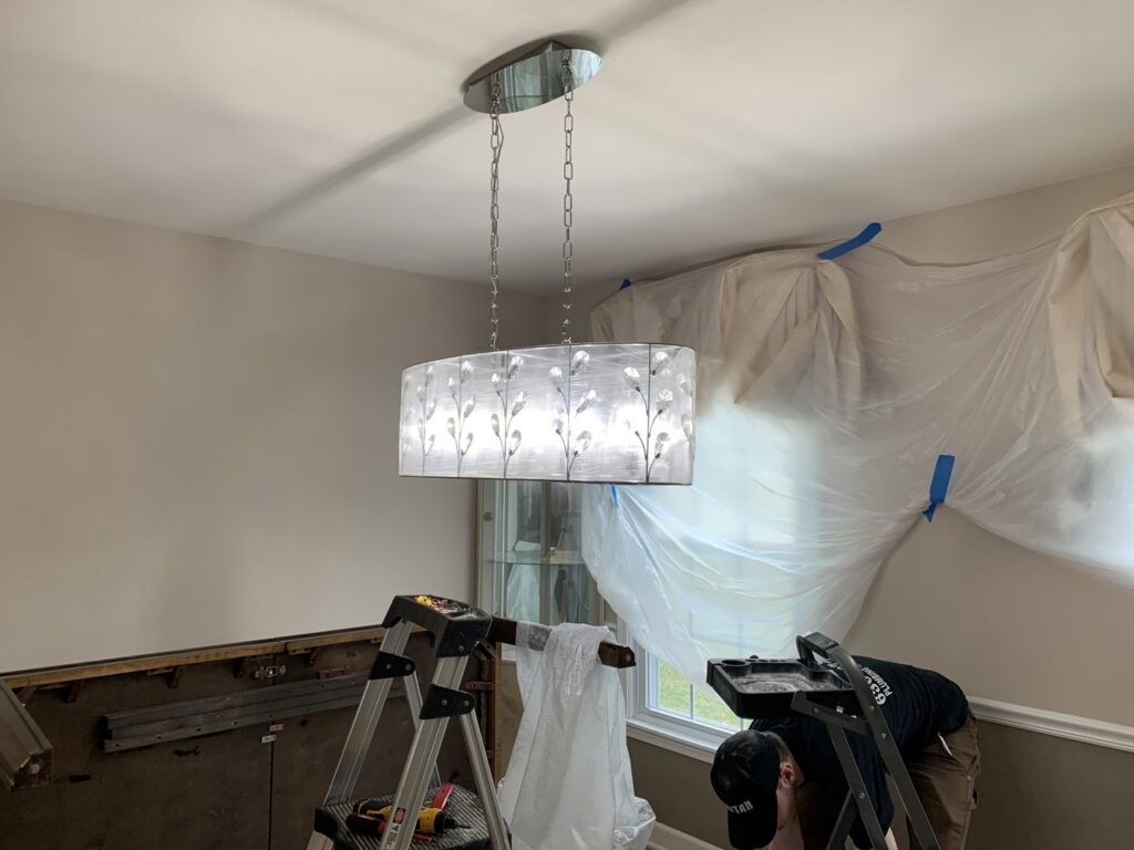 An electrician installing a new light fixture in a home for Tritan Services LLC in Naperville, IL