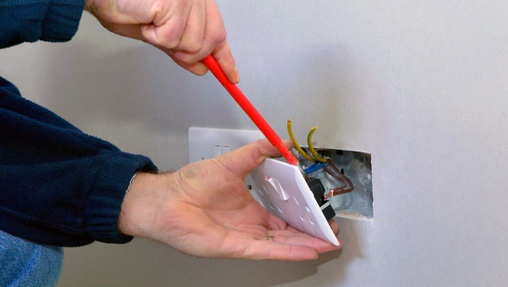 An electrician installing or repairing a light switch with exposed wiring, performed by Accuracy Electric Incorporation in Lakewood, CO.