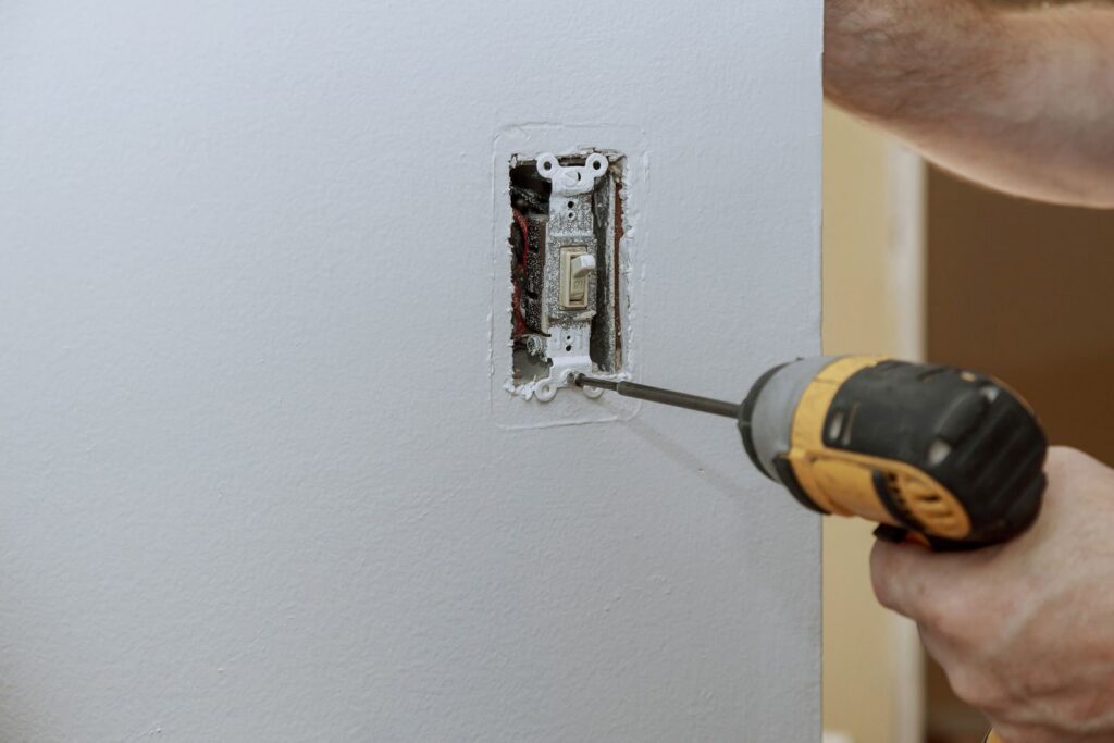 Electrician installing a light switch or outlet with a power drill for Omni Power Electrical Services LLC in San Antonio, TX